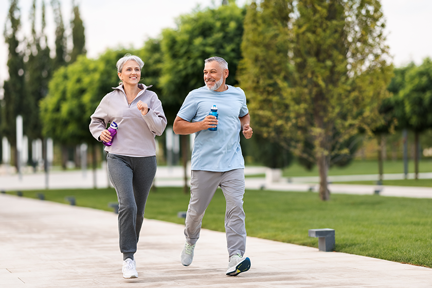 Full-length photo of lovely joyful retirees couple jogging