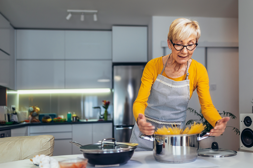 Happy senior woman cooking in her modern kitchen