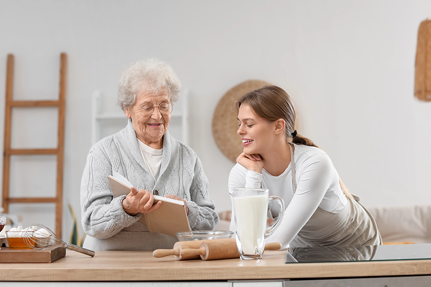 Young woman and her grandmother with recipe book